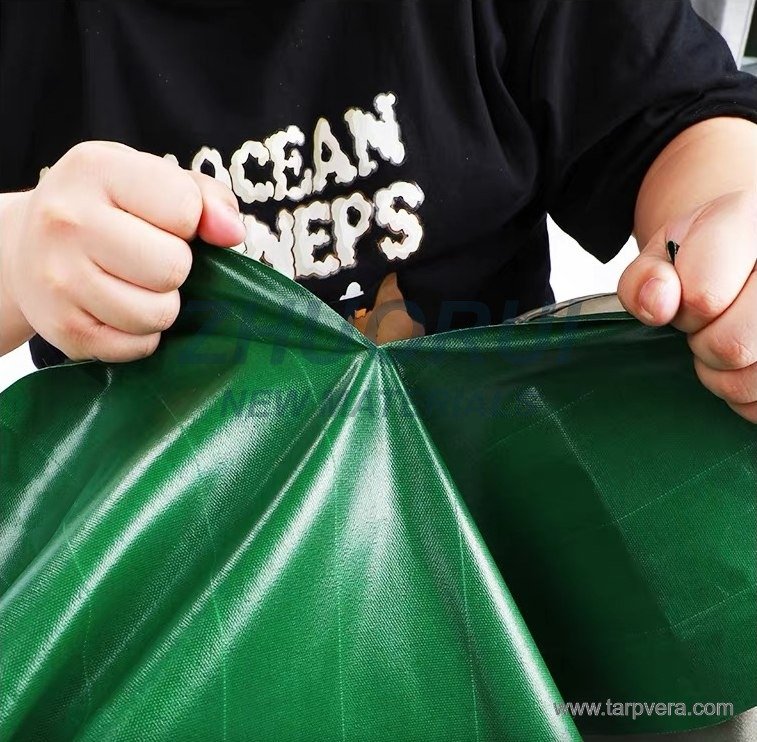Hand-pull demonstration showing tear and pull resistance of green PVC fabric