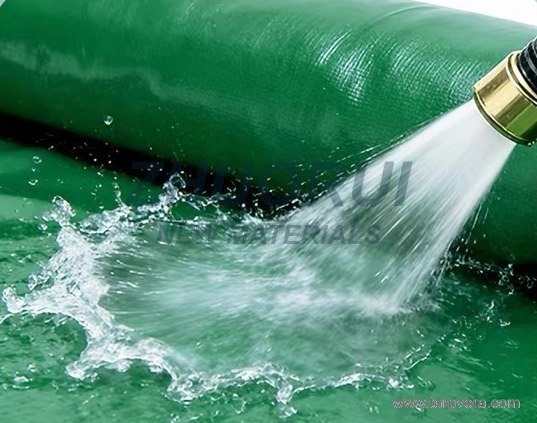 Hose spraying water onto green PVC fabric