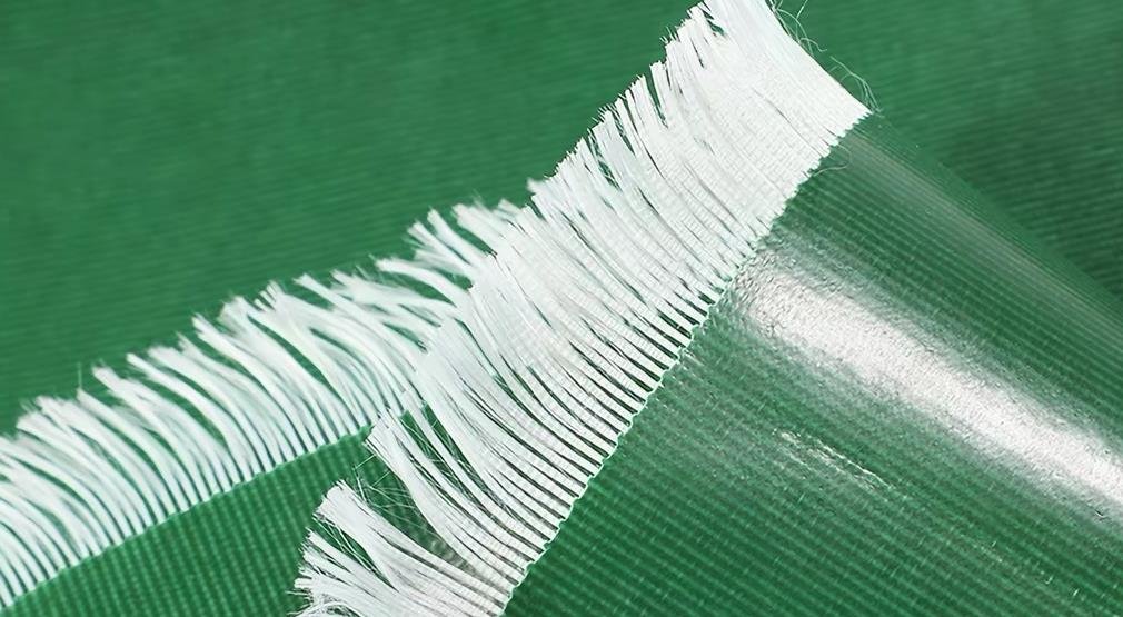Exposed woven threads beneath a green PVC coating
